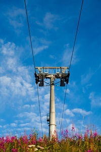 Low angle view of electricity pylon against blue sky