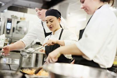 Male and female chefs cooking food in commercial kitchen