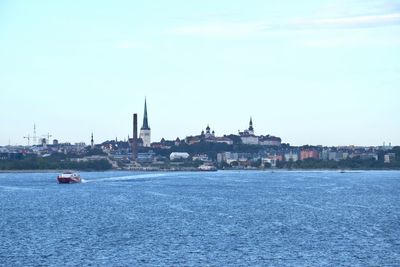 Sea by buildings in city against sky