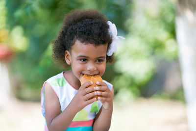 Girl eating bread while sitting outdoors