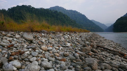 Stones by lake against sky