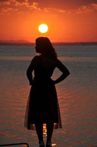 Silhouette woman standing on beach during sunset