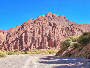 Panoramic view of rocky mountains against clear blue sky