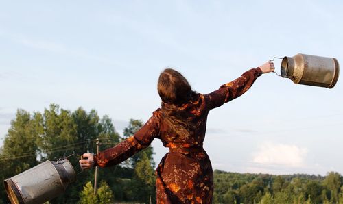 Rear view of woman holding umbrella against sky