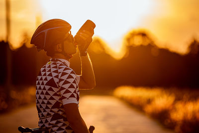 Woman wearing hat standing against sky during sunset
