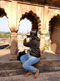 Rear view of man sitting at historic building