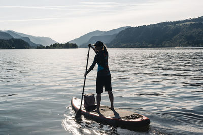 A young woman paddles a sup on the columbia river during a sunny day.