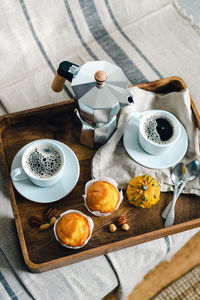 Morning coffee with pumpkin muffins on a wooden tray.