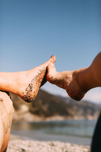 Close-up of couple touching feet at beach