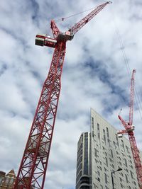 Low angle view of crane against cloudy sky