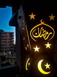 Low angle view of illuminated sign against sky at night