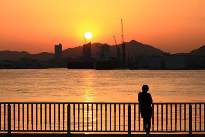 Silhouette of people standing by river during sunset