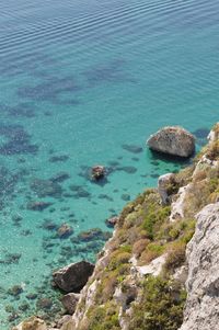 High angle view of rocks at shore against blue sky