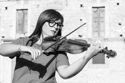 Woman playing violin during sunny day