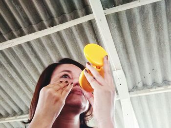 Woman applying make-up while looking in hand mirror