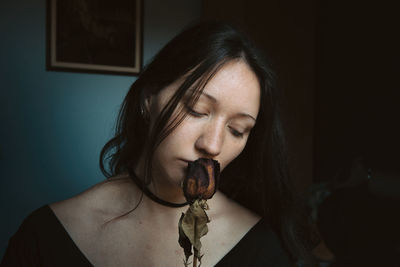 Close-up of beautiful woman with rose at home