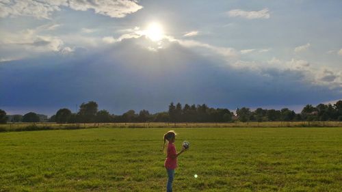 Girl standing on field against sky