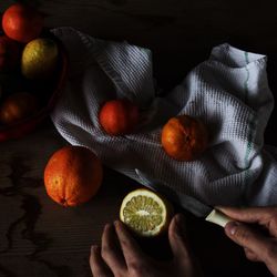 Cropped imaged of person cutting oranges on table