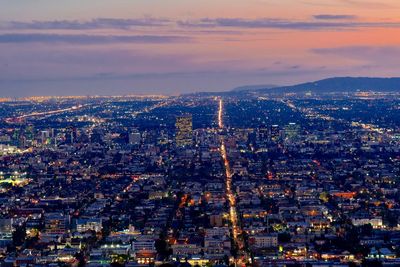 Aerial view of illuminated city buildings during sunset