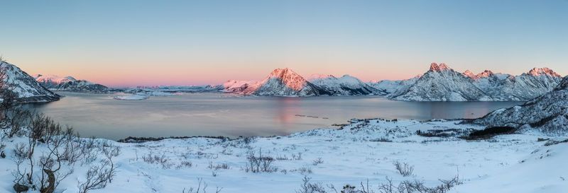 Panoramic shot of river by snowcapped mountains against sky during sunset