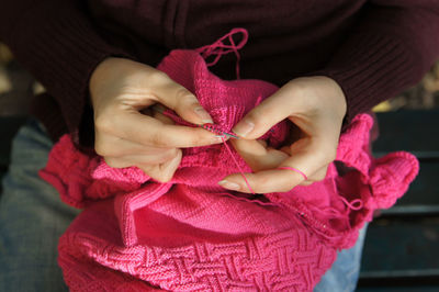 Midsection of woman knitting pink wool