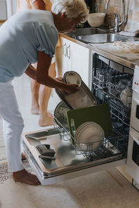 Senior woman putting dishes in dishwasher