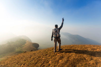 Rear view of man standing on mountain against sky