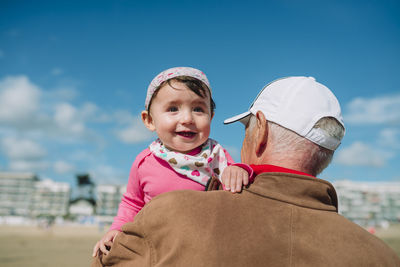 France, la baule, portrait of baby girl on grandfather's arms on the beach