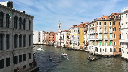 Canal amidst buildings in city against sky