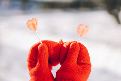 Valentines day card. woman in red mittens holding two heart shaped lollipops. i love you