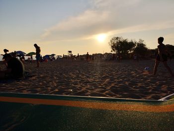 People on beach against sky during sunset