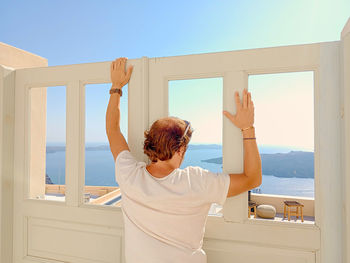 Rear view of man looking scenic view through window