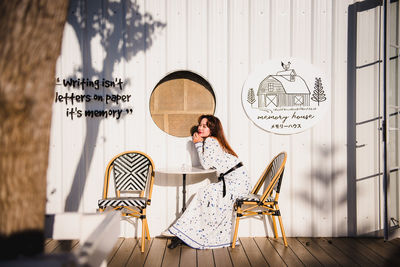 Woman sitting on seat against wall