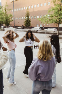 Teenage girls dancing while female friend recording video on smart phone at skateboard park