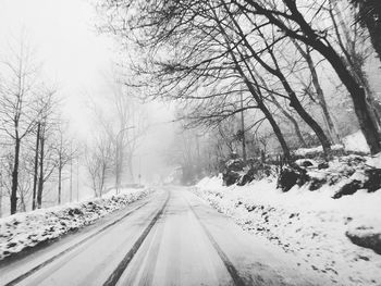 Road amidst snow covered trees against sky