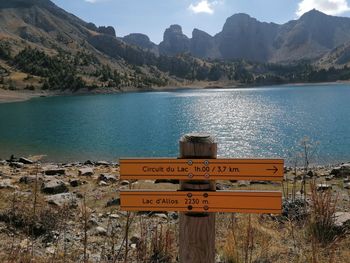 Information sign by lake against mountains