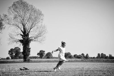 Girl running on field against clear sky