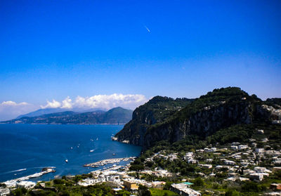 Aerial view of city by sea against blue sky