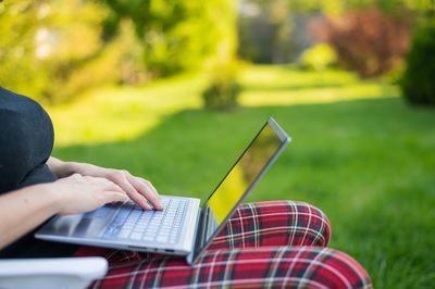 Midsection of woman using laptop while sitting on bench