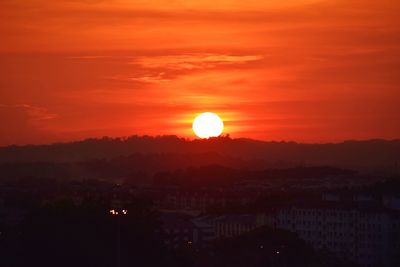 Scenic view of silhouette city against romantic sky at sunset