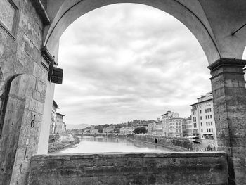 Arch bridge over old buildings against sky in city