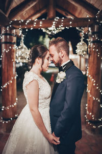 Newlywed couple holding hands facing each other , bride in white groom in blue