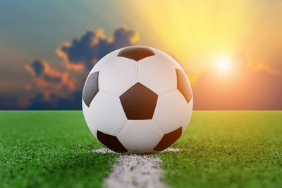 Digital composite of soccer ball on playing field against sky 