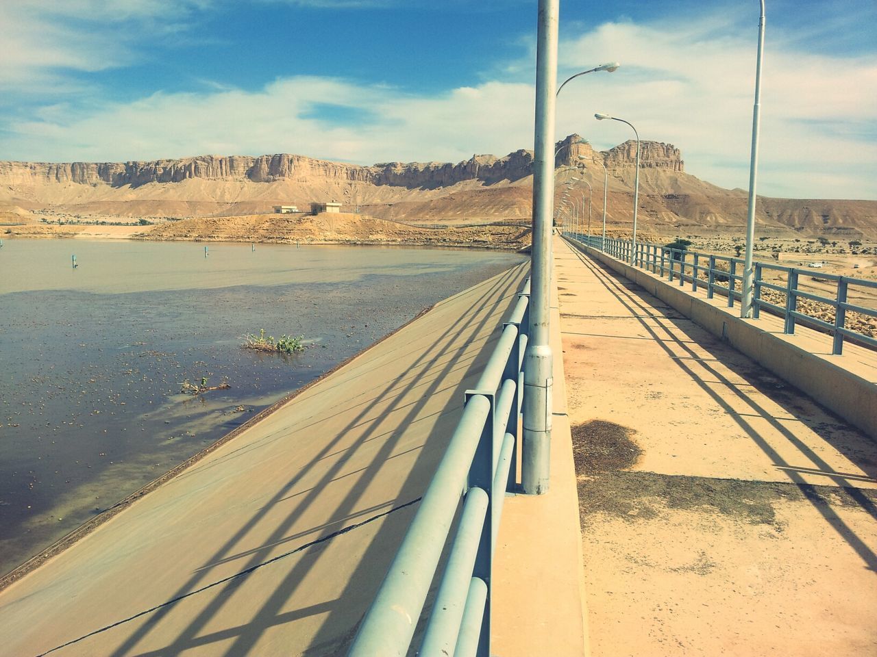 transportation, sky, the way forward, cloud - sky, built structure, mountain, architecture, railroad track, diminishing perspective, connection, vanishing point, cloud, rail transportation, day, mode of transport, road, outdoors, travel, railing, no people