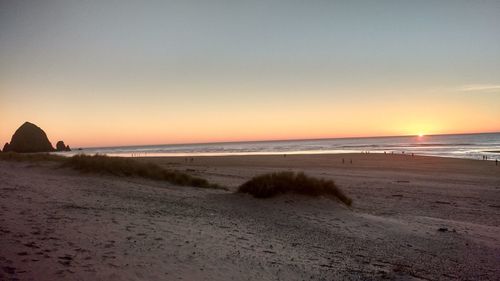 Scenic view of beach against clear sky during sunset