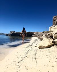 Woman on beach against clear sky