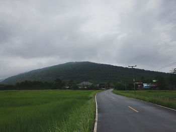 Road amidst field against sky