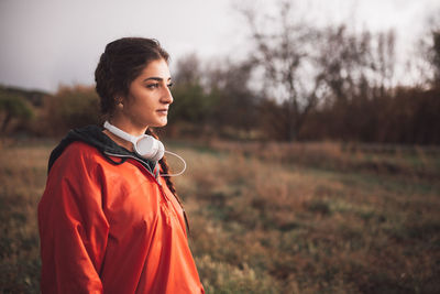 Young woman looking away while standing on field