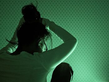 Rear view of woman tying hair at home