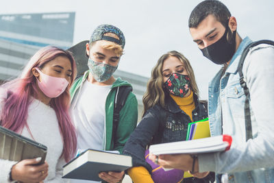 Friends wearing masks studying outdoors